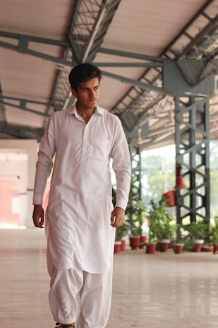 A man in a white outfit walking in a building