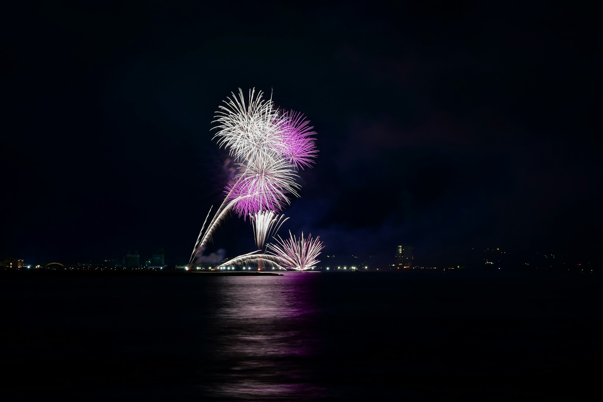 Fireworks are lit up in the night sky over the water