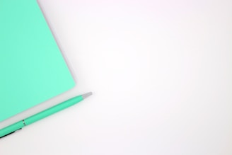 A green notebook with a pen on top of it