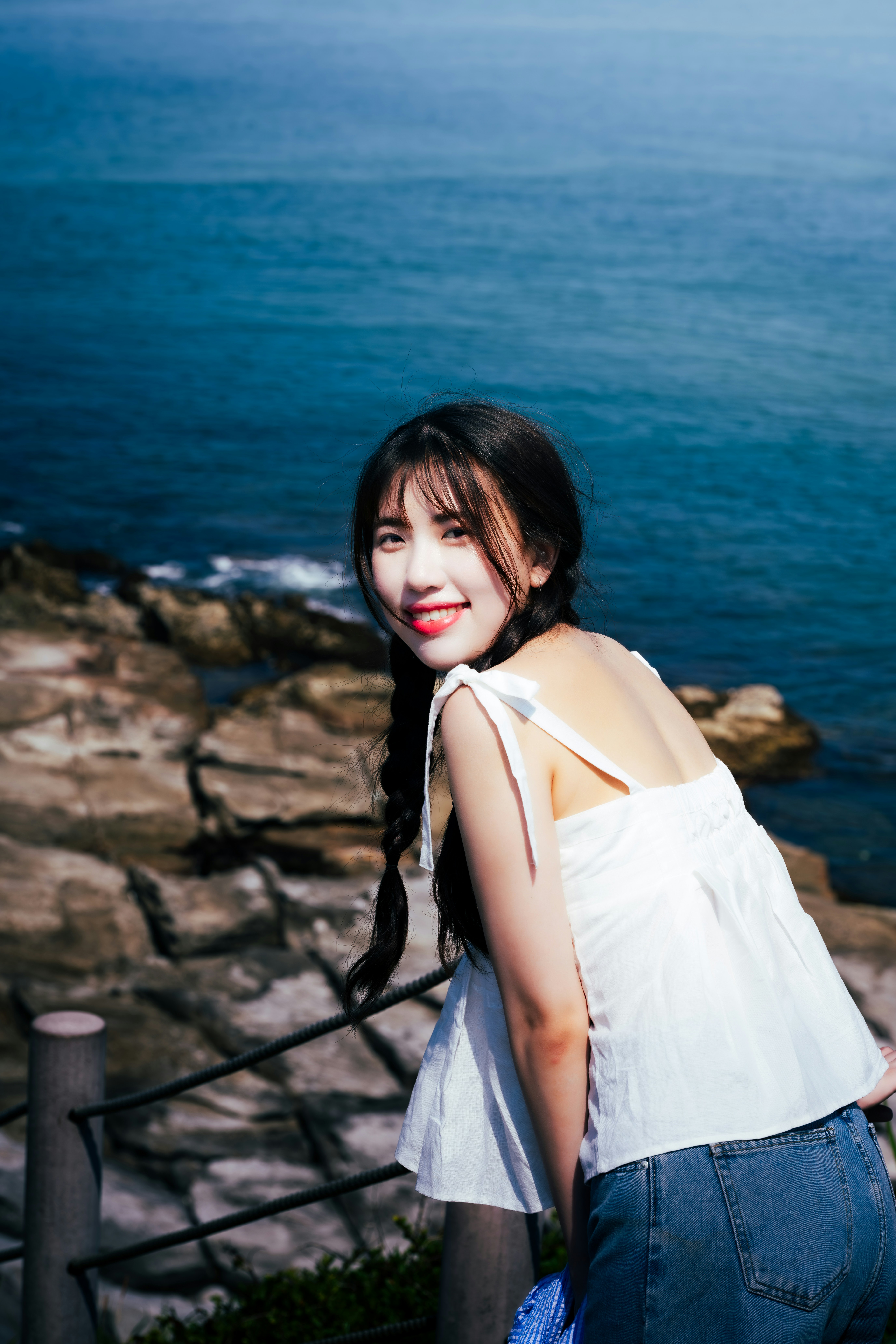 허리에 손을 얹고 바다 옆에 서 있는 여자