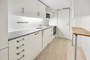 A kitchen with white cabinets and a wooden table