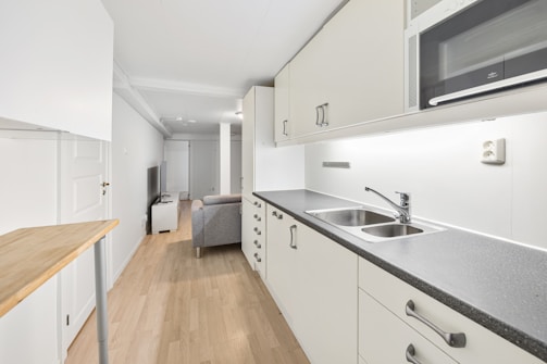 A kitchen with white cabinets and black counter tops