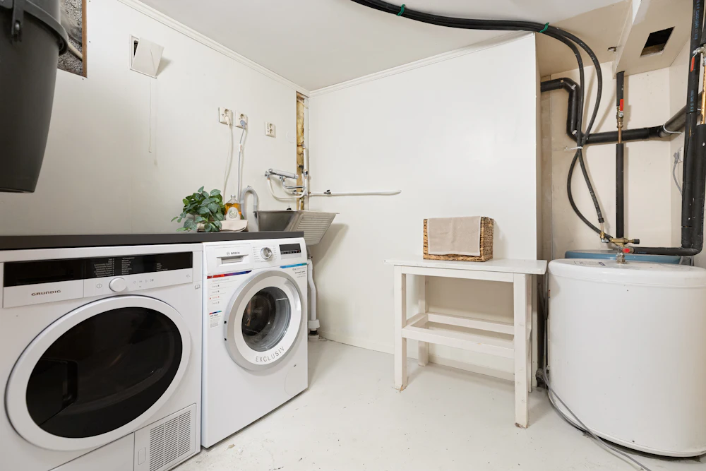 Modern laundry room with white washer, dryer, utility sink, and storage shelving