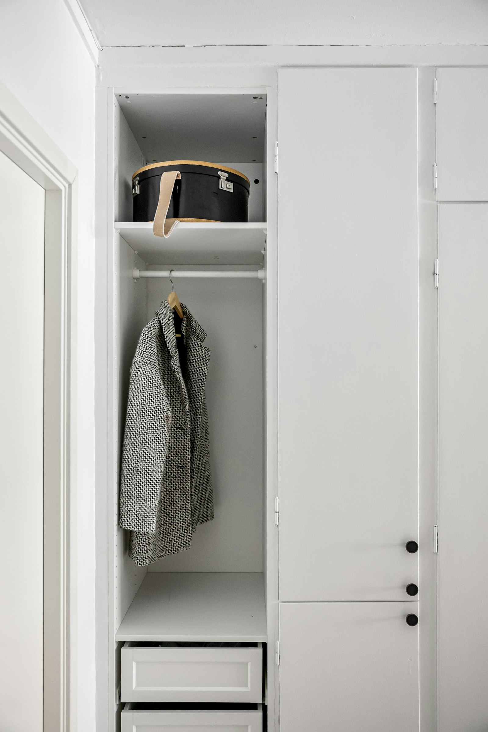 A white closet with a single coat hanging inside