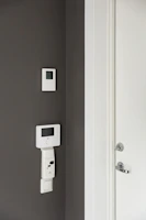 A bathroom with a toilet and a wall mounted thermostaer