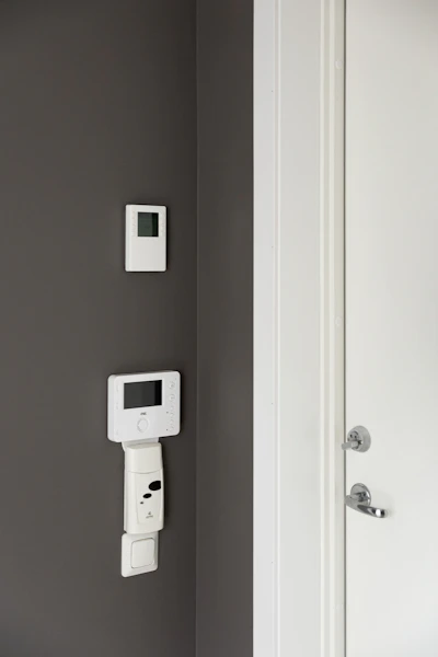 A bathroom with a toilet and a wall mounted thermostaer