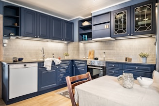 A kitchen with blue cabinets and a white table