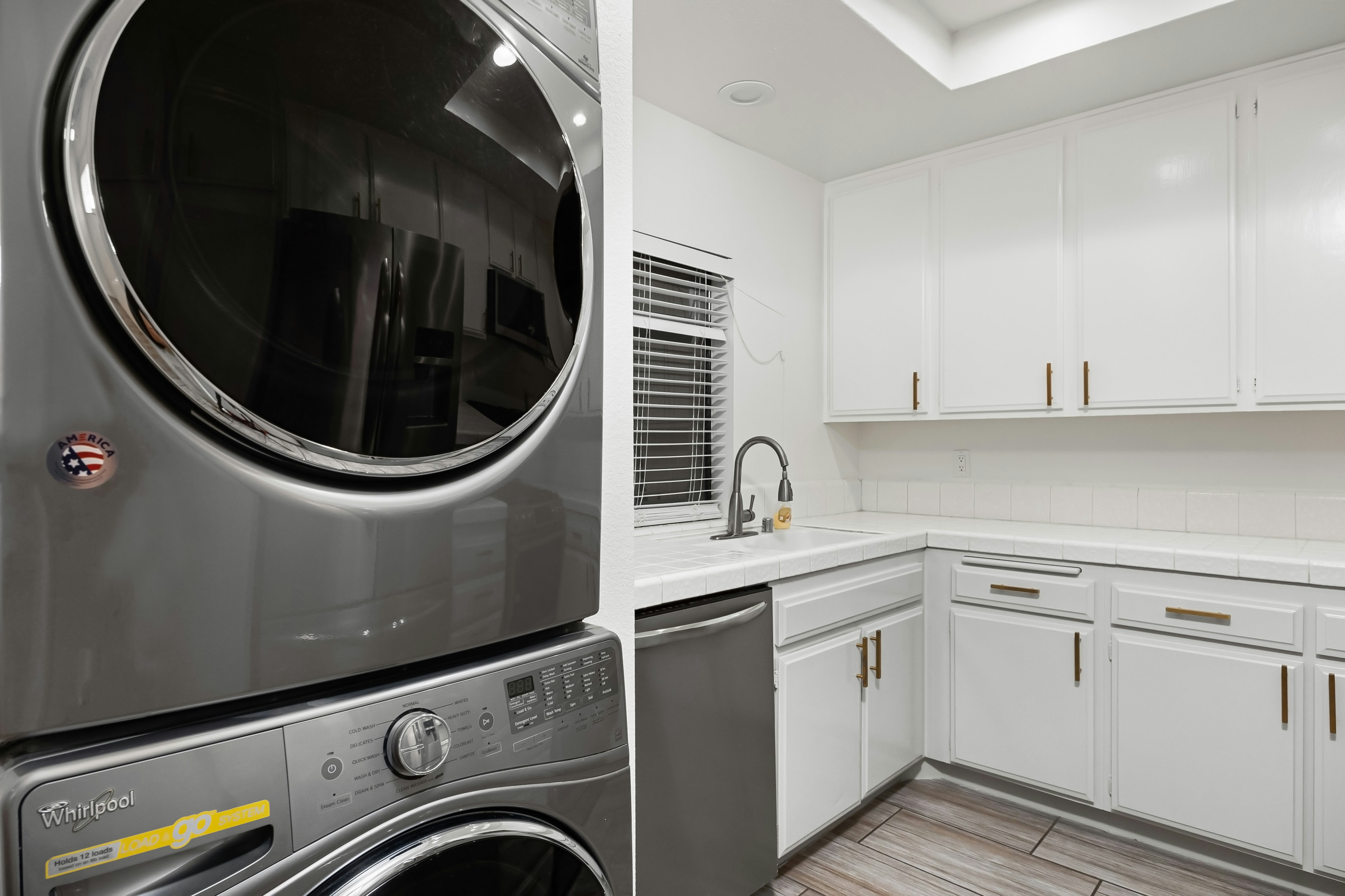 A washer and dryer in a kitchen with white cabinets