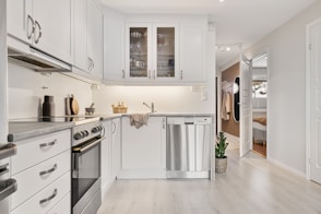 A kitchen with white cabinets and wood floors