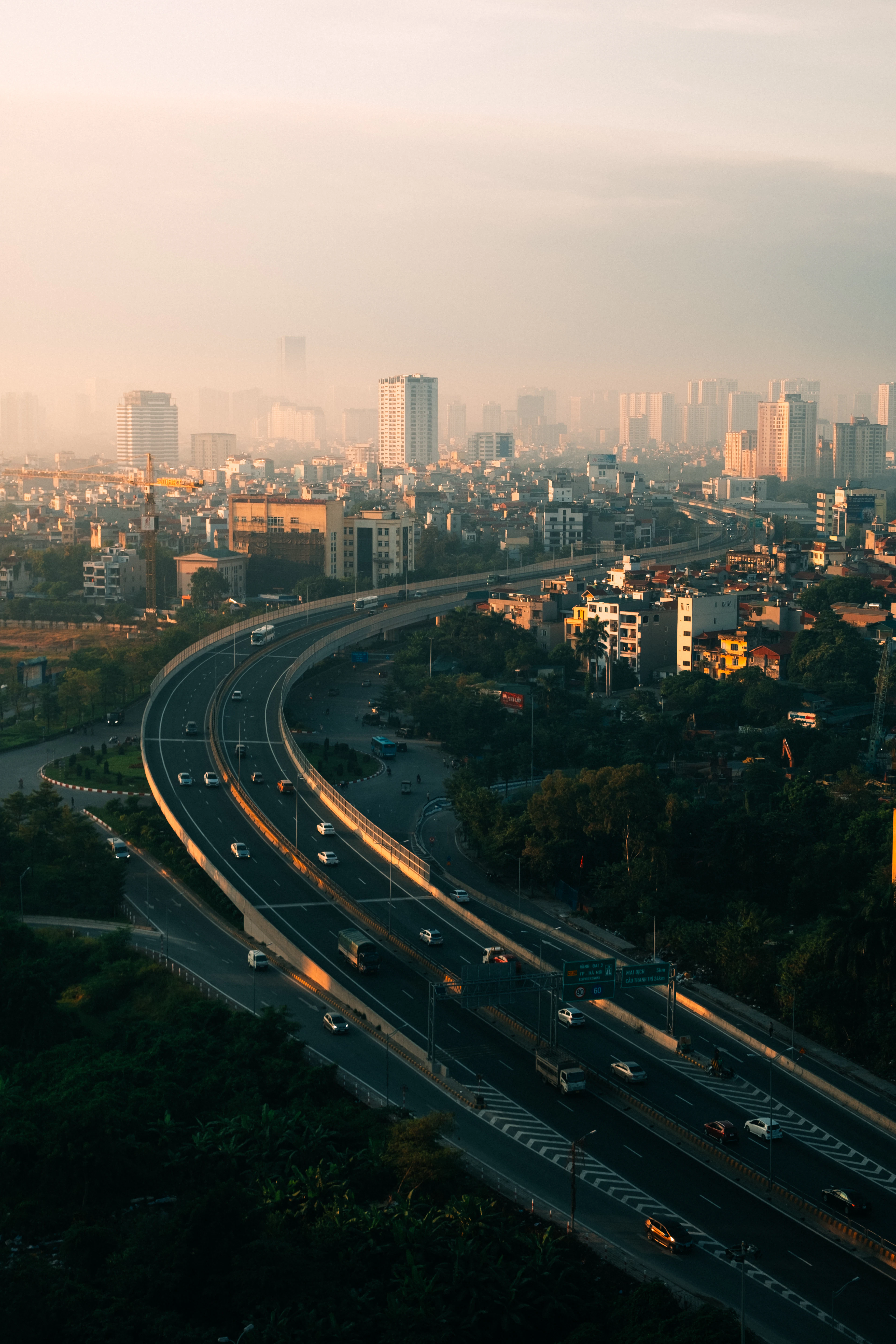 Hanoi's skyline glows at dawn as an elevated highway curves through the misty city.