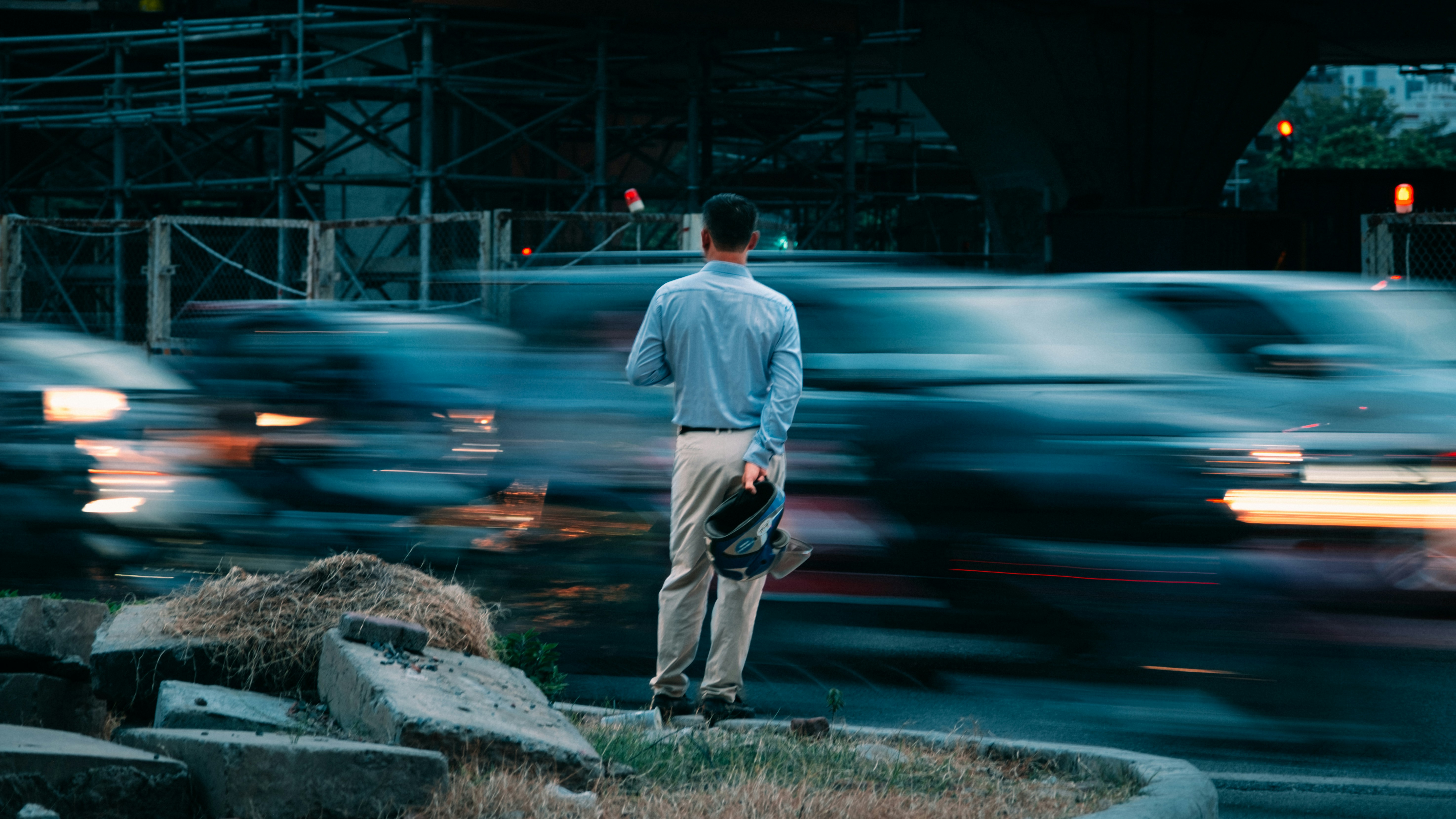 A man standing on the edge of a road in front of a bunch of cars