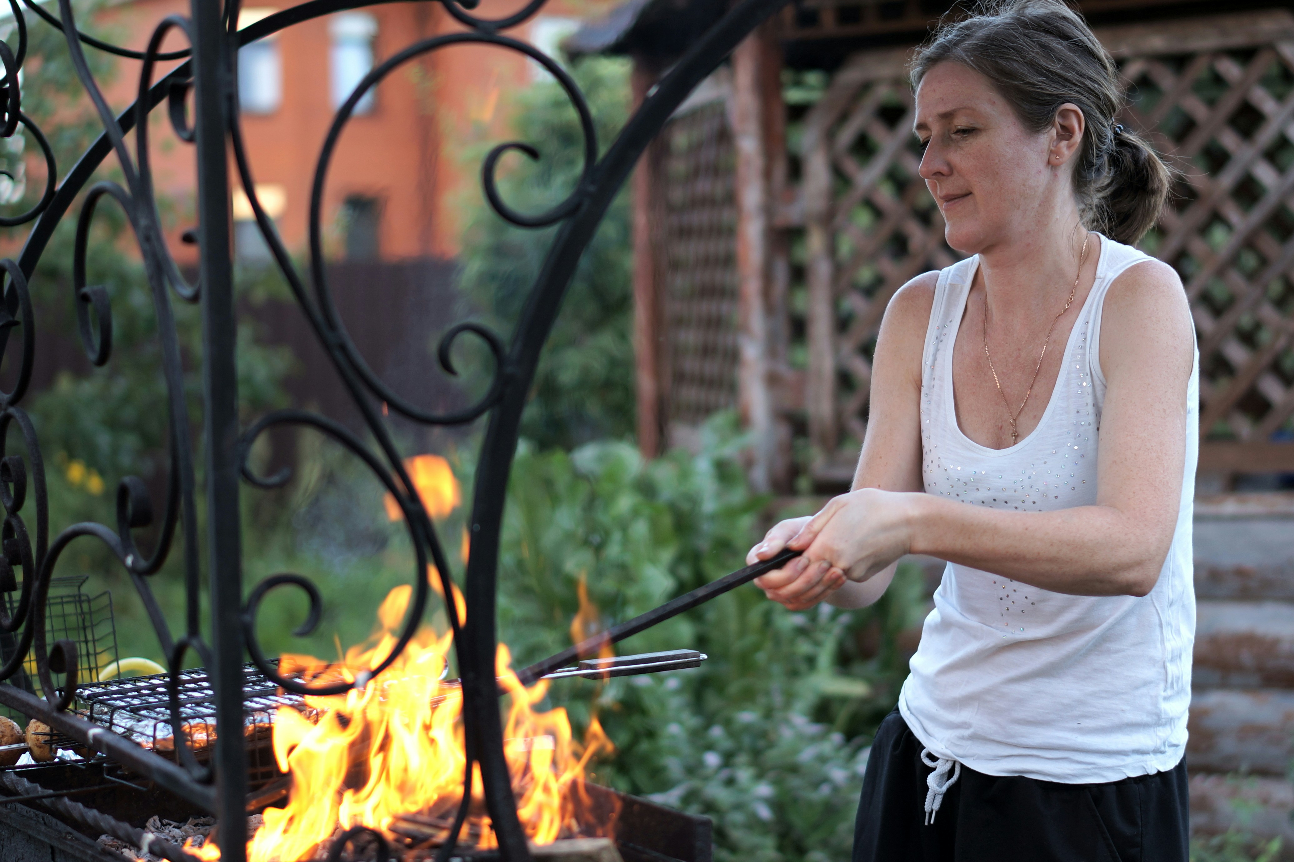 A woman is cooking on a grill outside