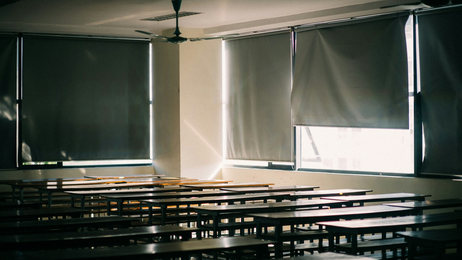 A classroom with rows of desks and windows