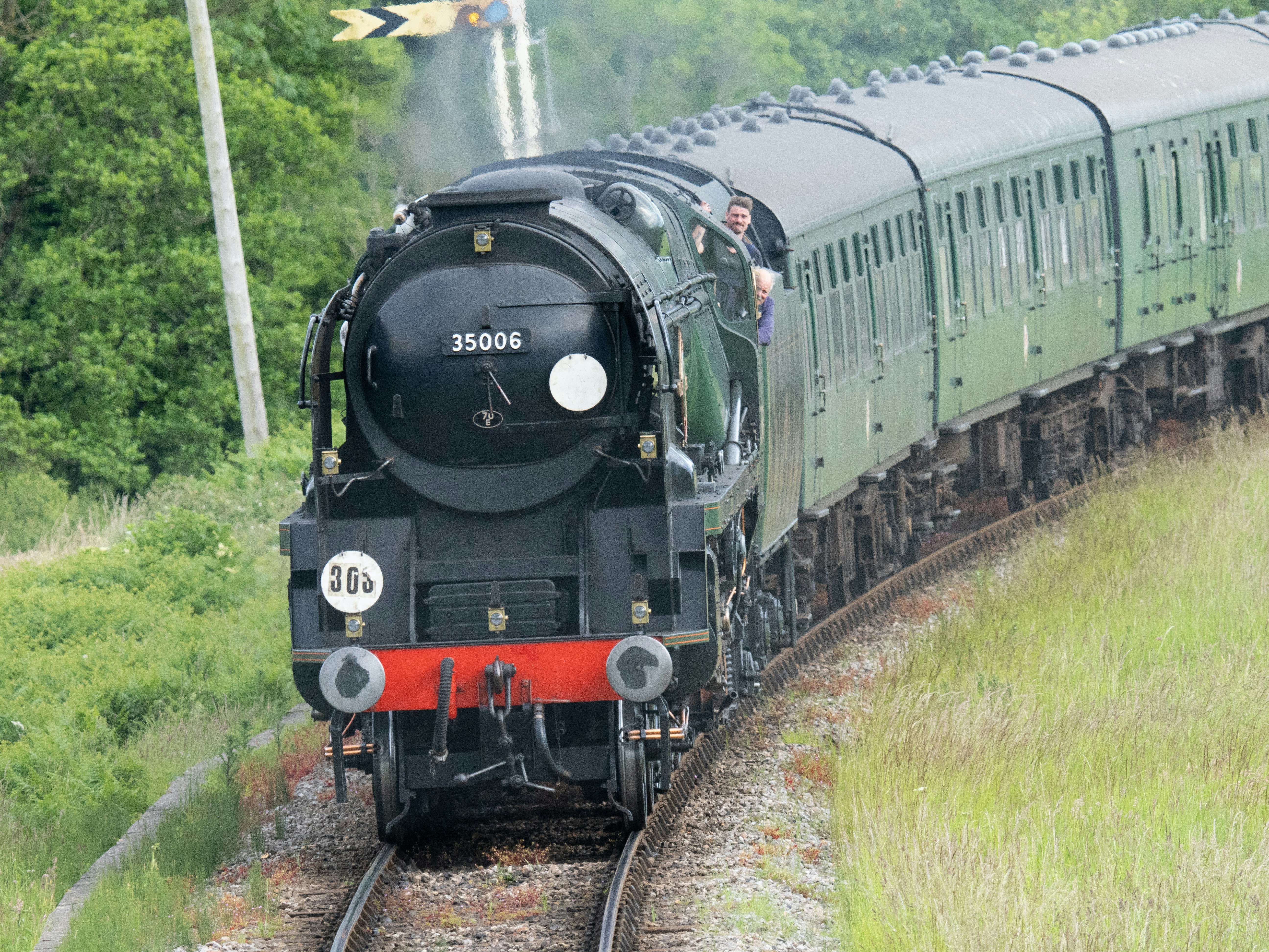 A train traveling down tracks next to a lush green forest photo Free