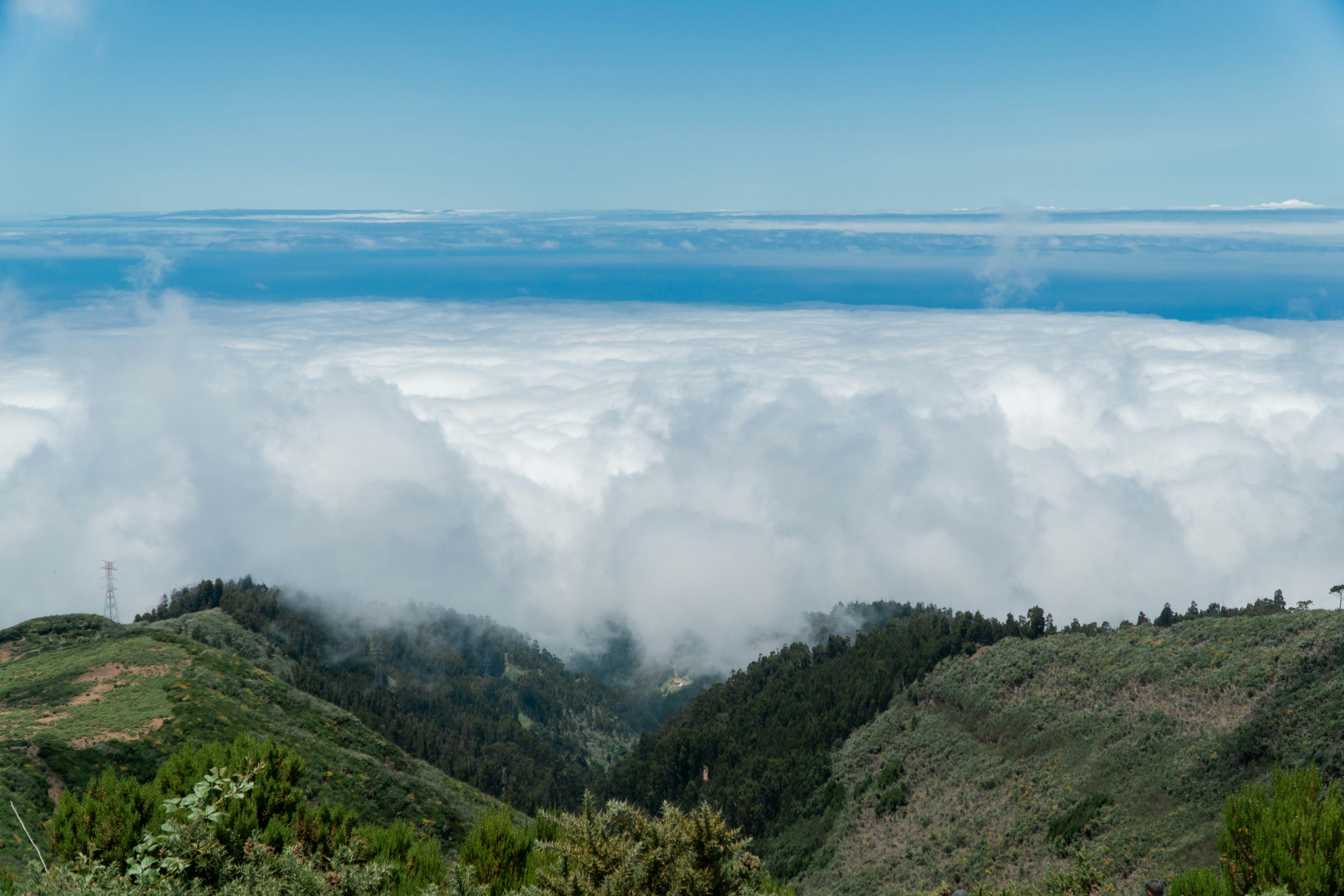 A view of the clouds and mountains from the top of a hill
