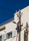 A man on a ladder working on a telephone pole
