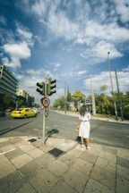 A woman standing on the side of a road next to a traffic light