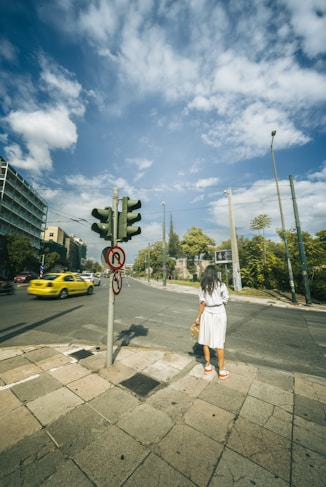 A woman standing on the side of a road next to a traffic light
