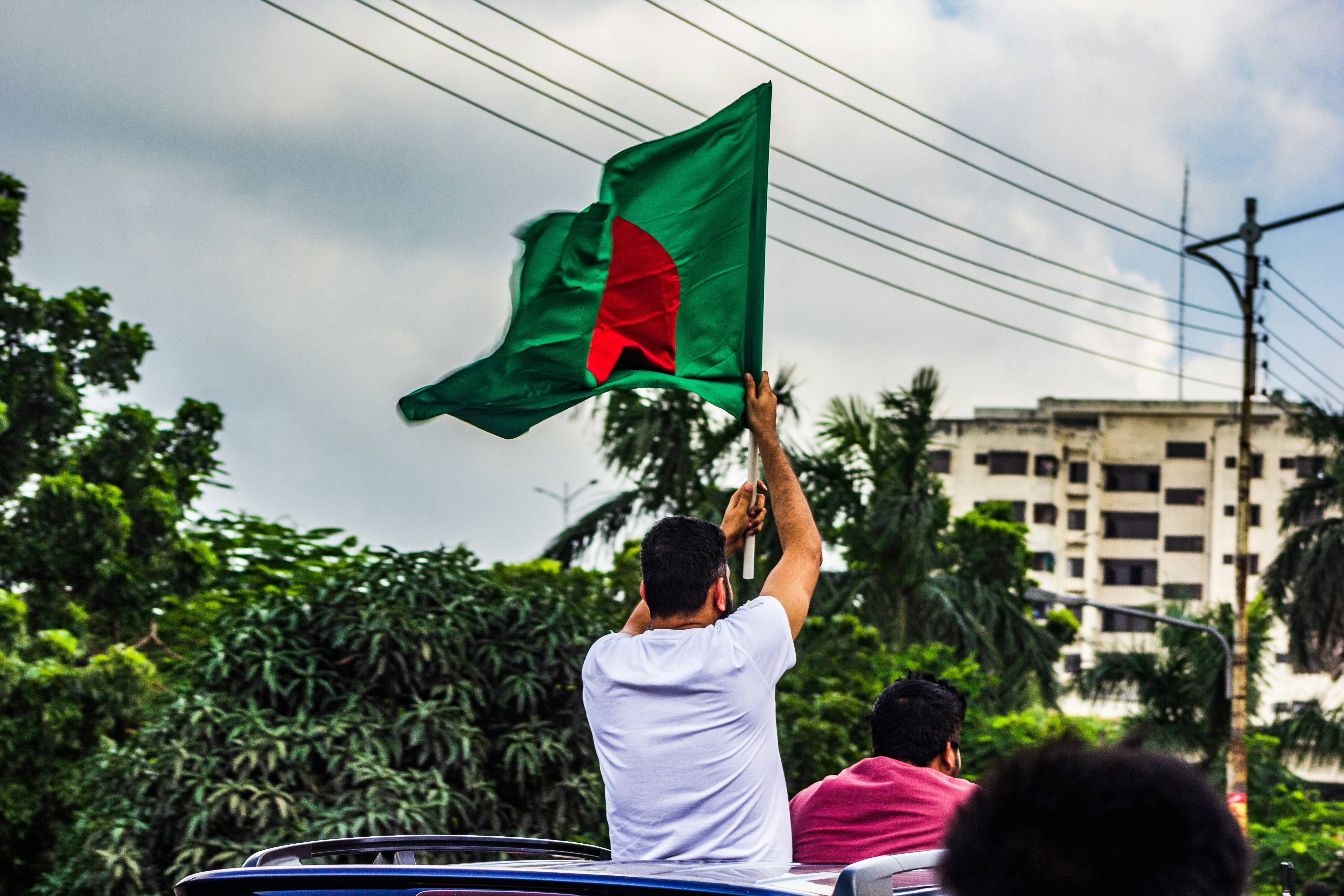 A group of people riding in a car with a flag