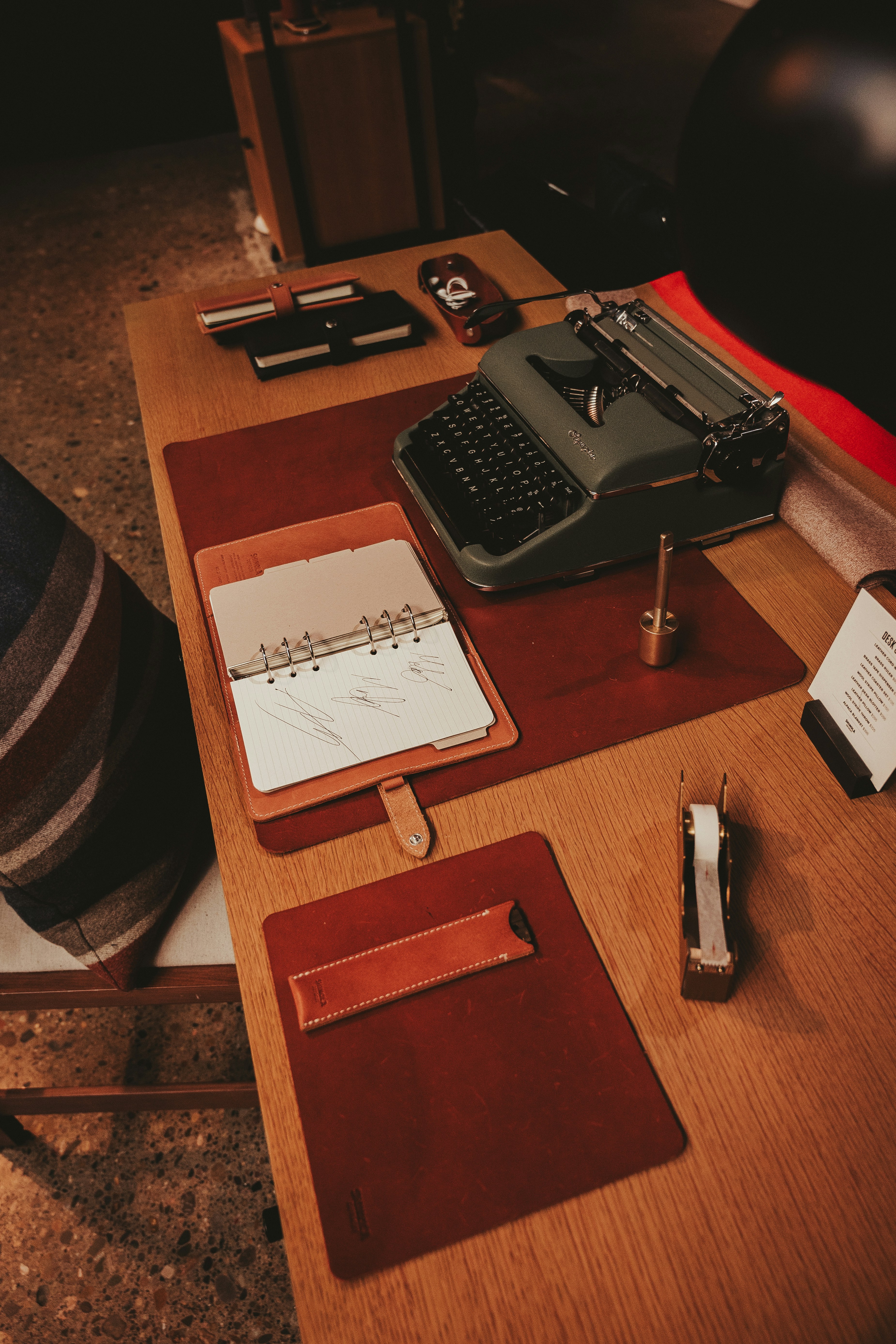 A desk with a typewriter, notebooks, and other items on it