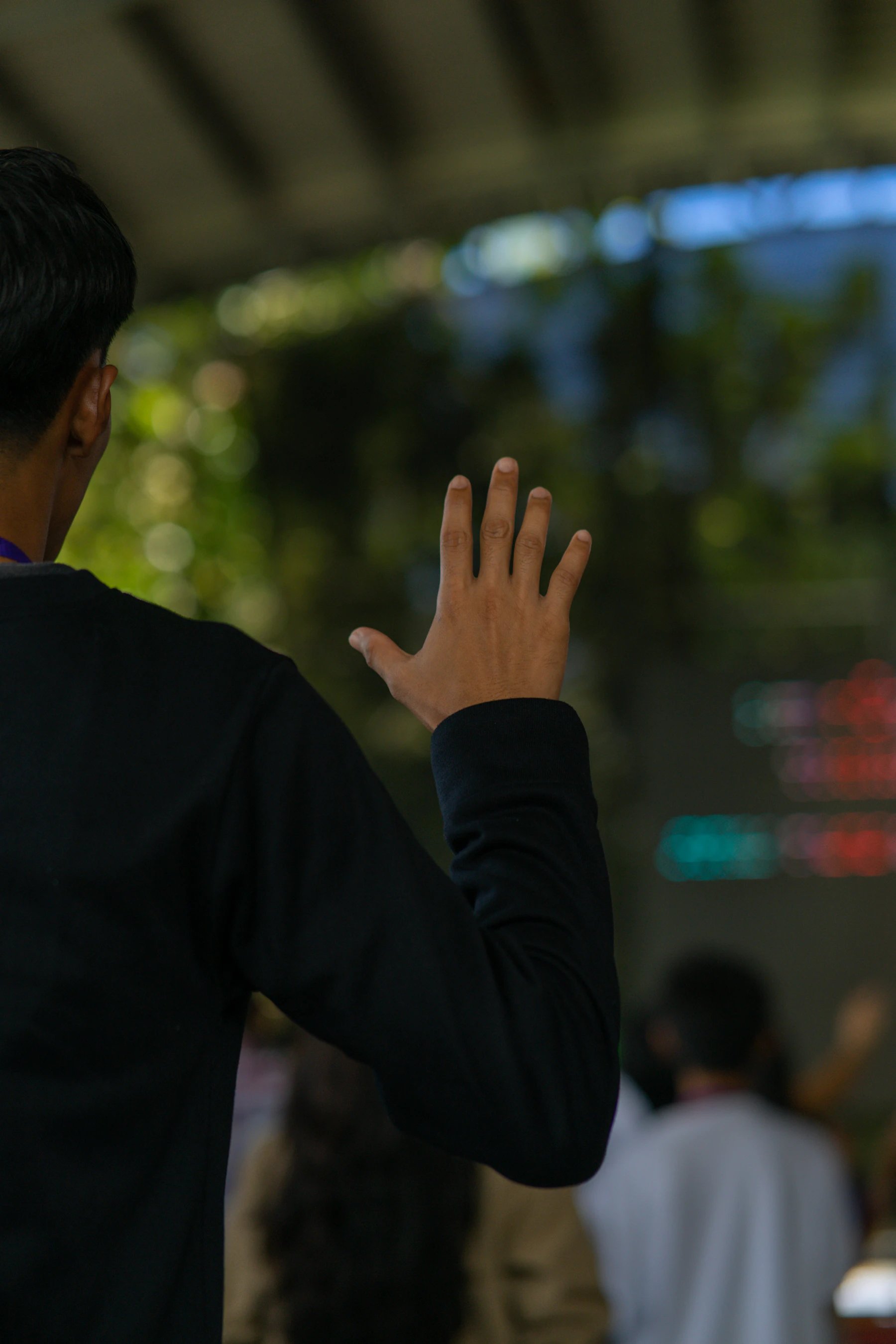 A man addressing a gathering with one hand raised