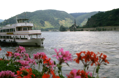 A boat floating on top of a river next to a lush green hillside