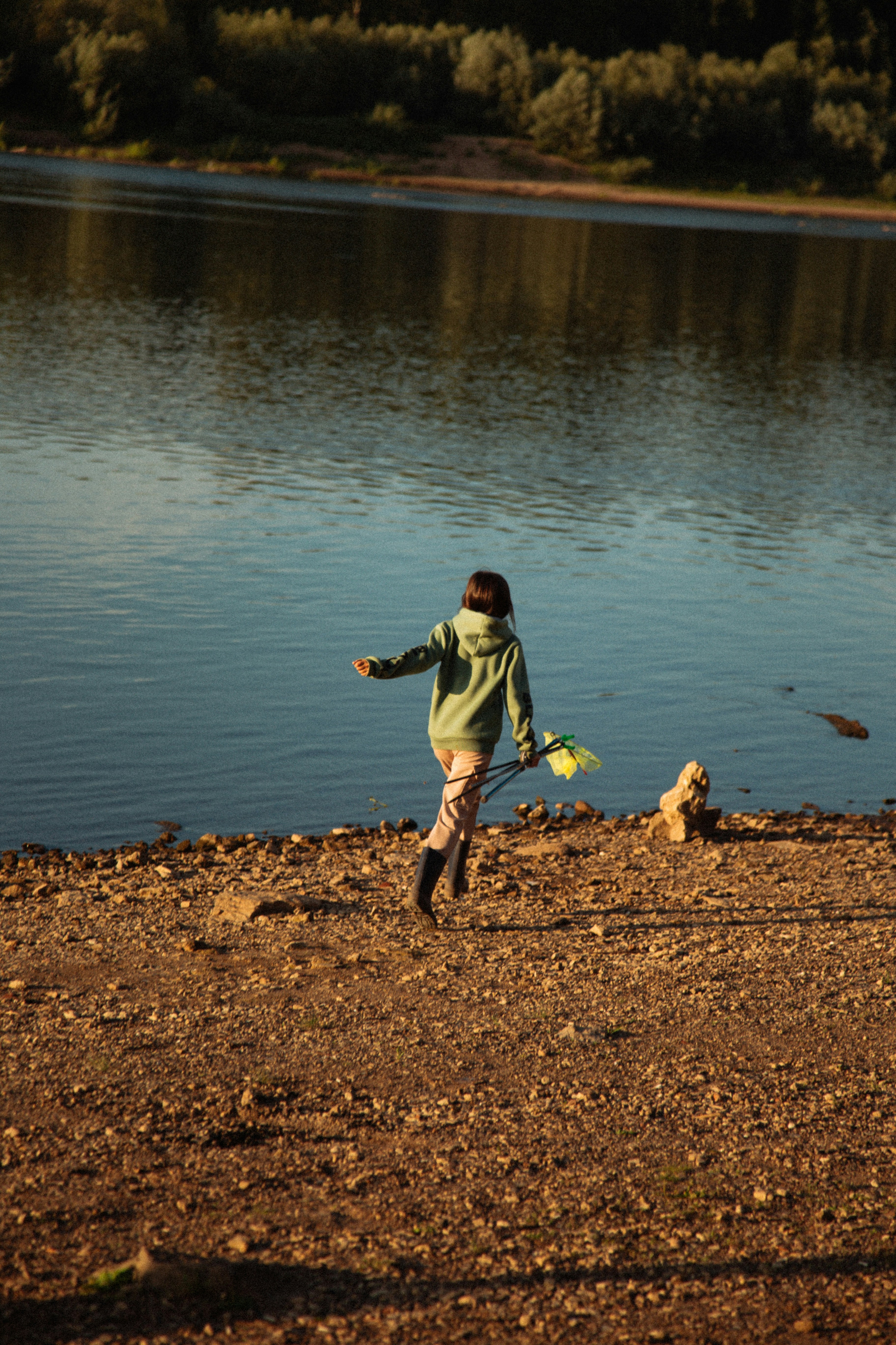 A young girl is throwing a frisbee at a lake