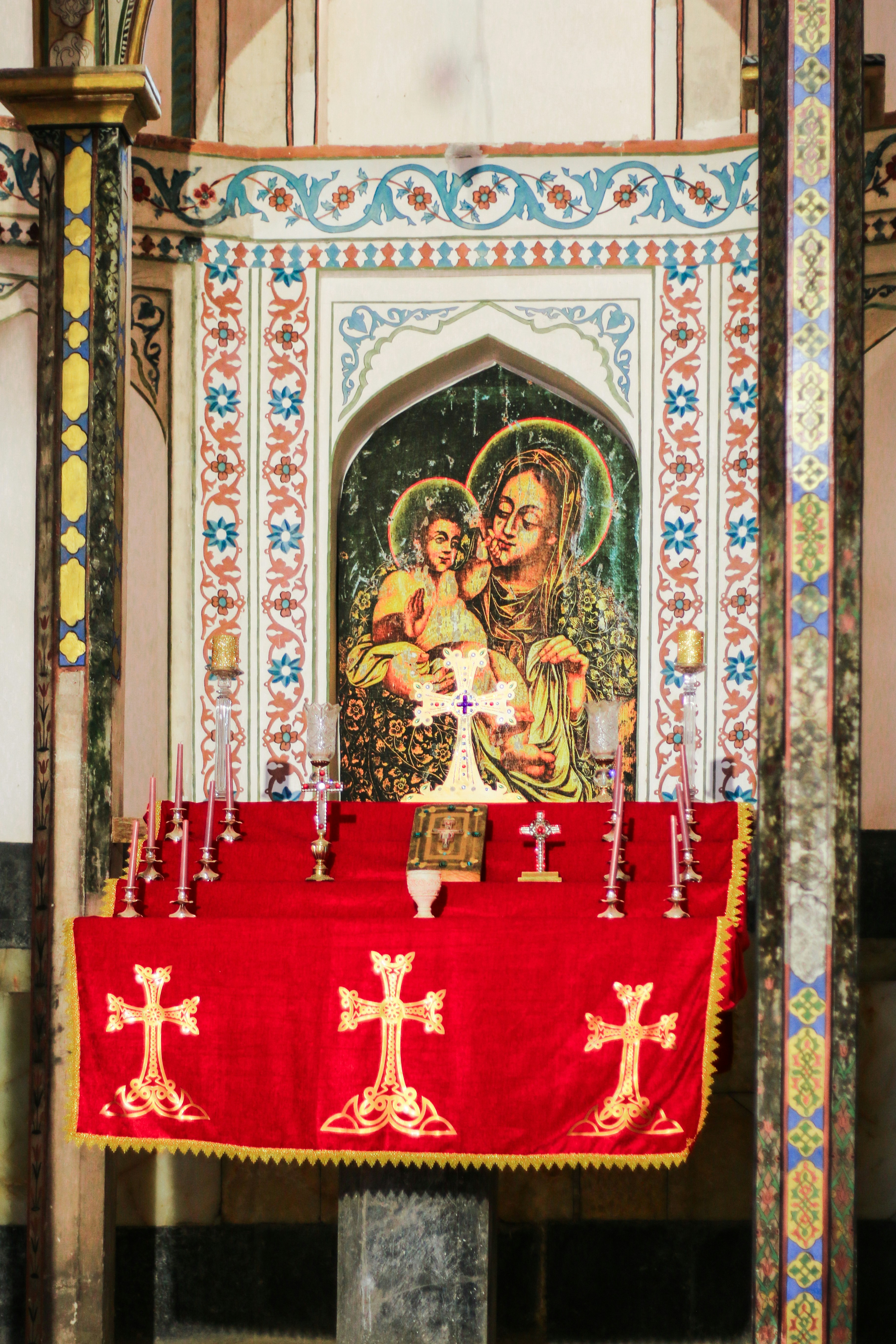 A church alter with a red cloth and candles