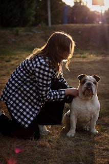 A woman kneeling down next to a dog