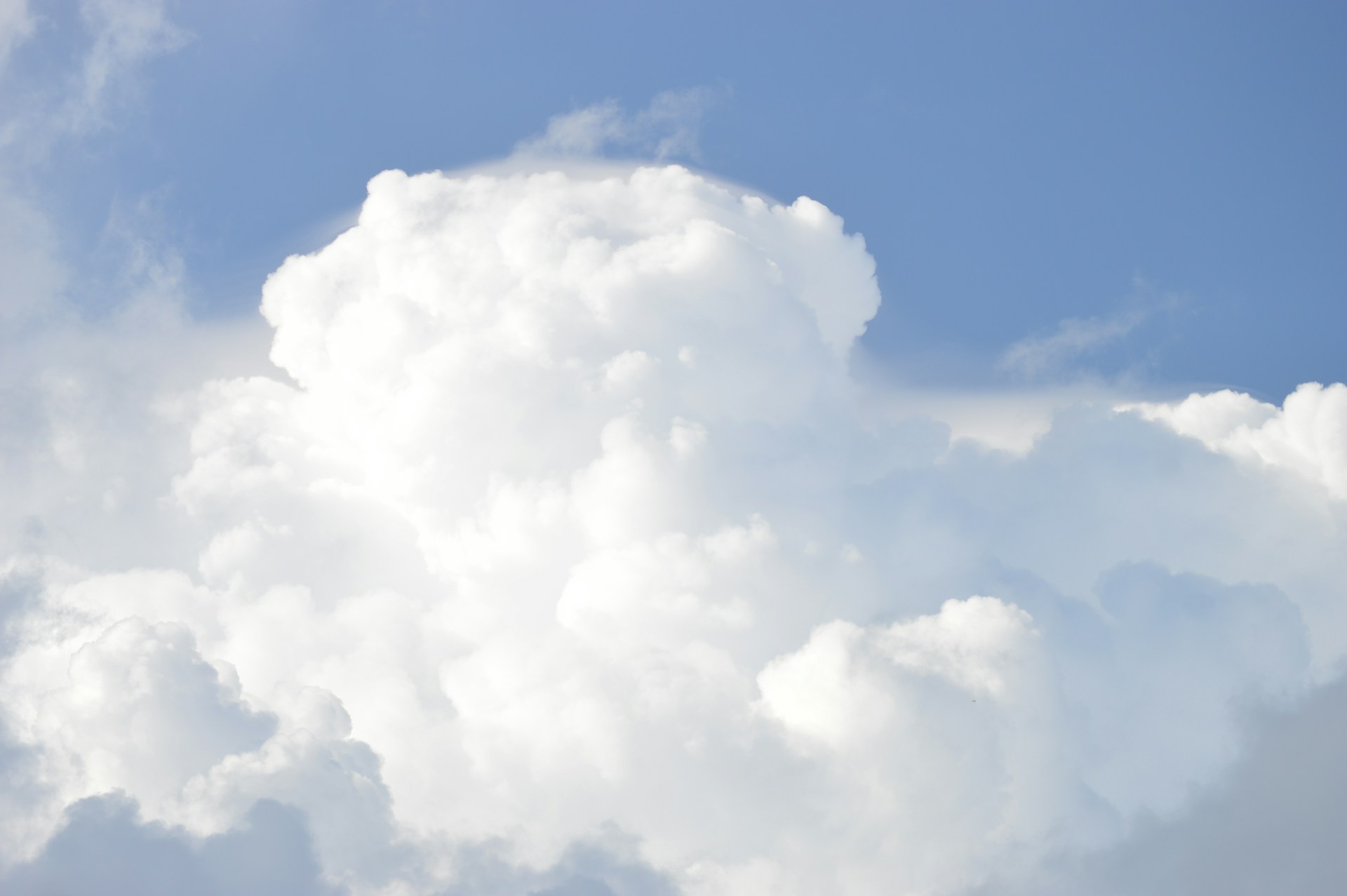 A plane flying through a cloudy blue sky