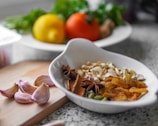 A bowl of food sitting on top of a wooden cutting board