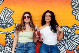 Two women standing next to each other in front of a wall