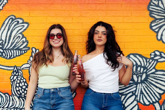 Two women standing next to each other in front of a wall