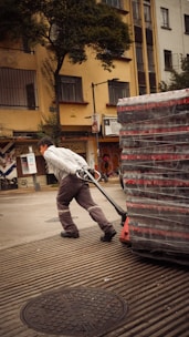A man is pushing a cart of boxes down the street