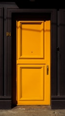 A bright yellow door sits in front of a black building