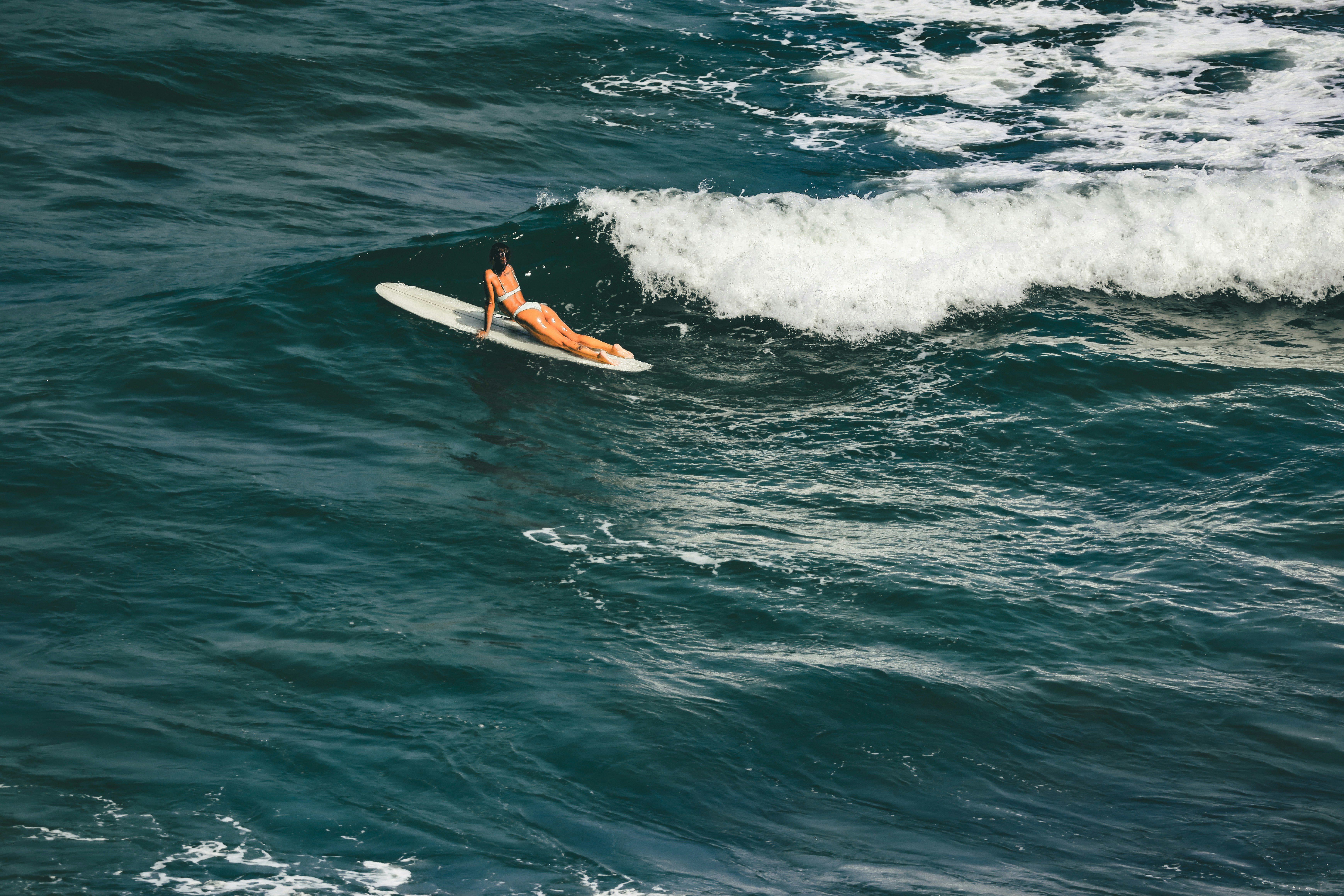 A person laying on a surfboard in the ocean