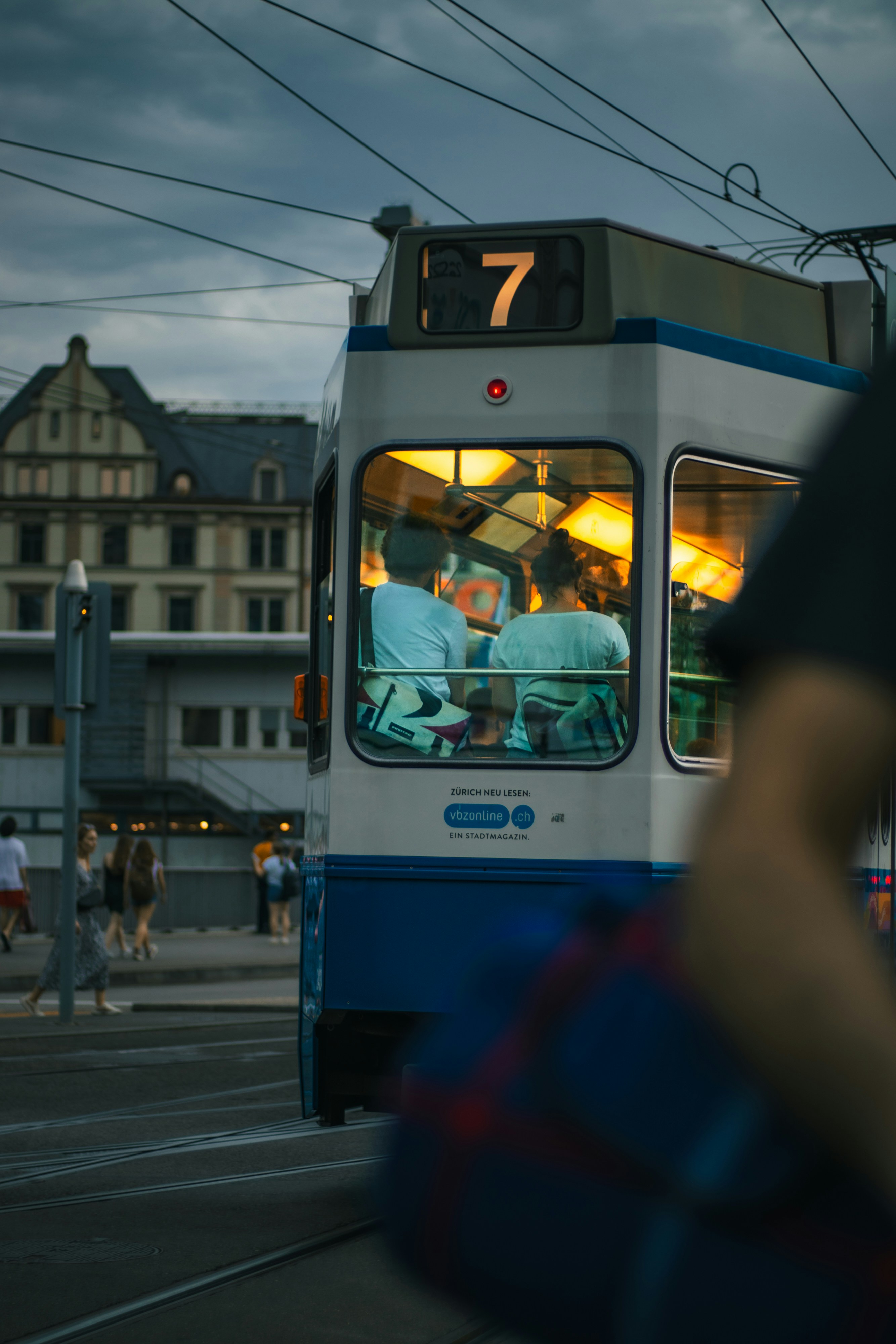 A blue and white bus driving down a street next to a tall building