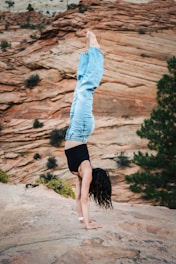 A woman doing a handstand on top of a rock