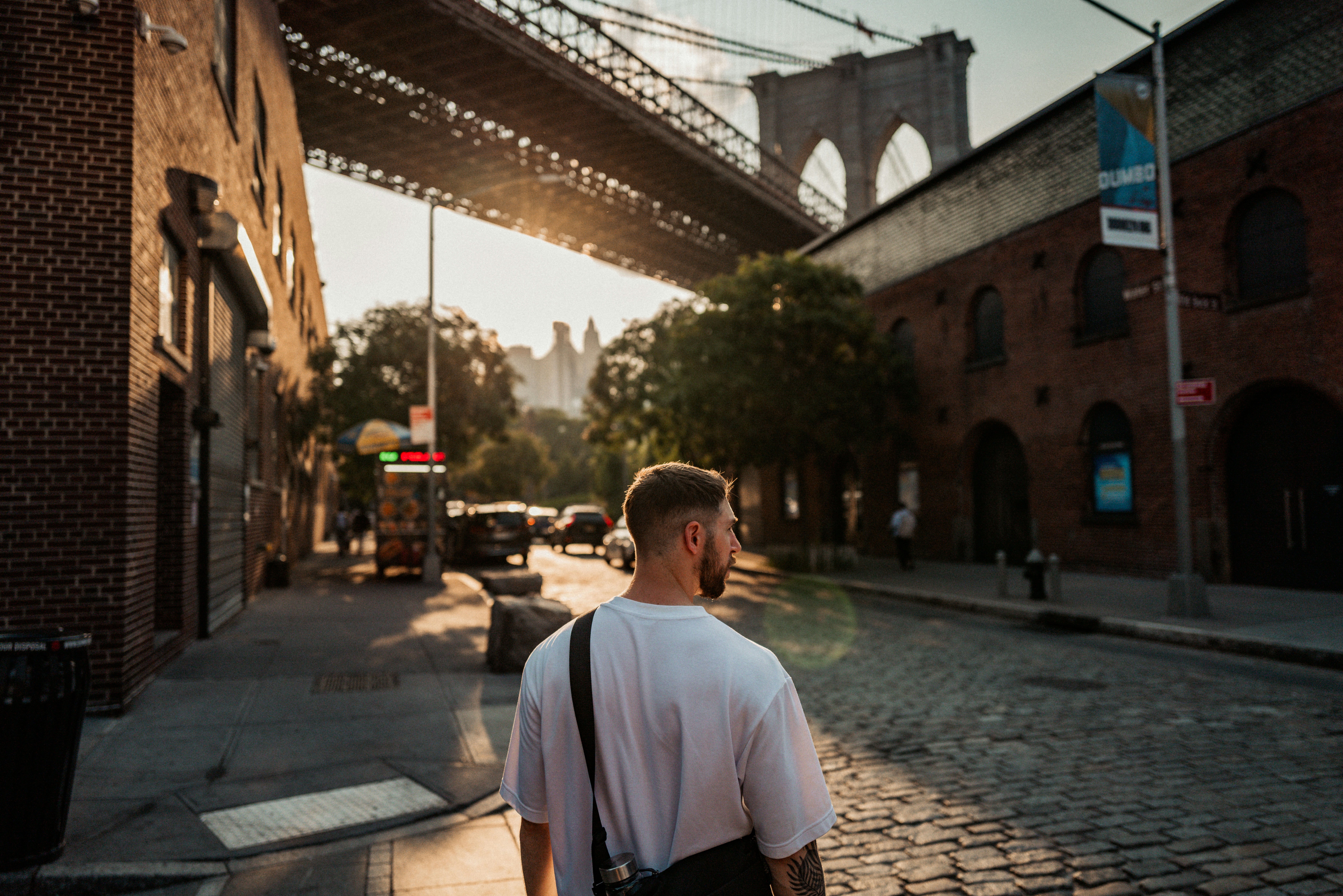 A man walking down a street under a bridge