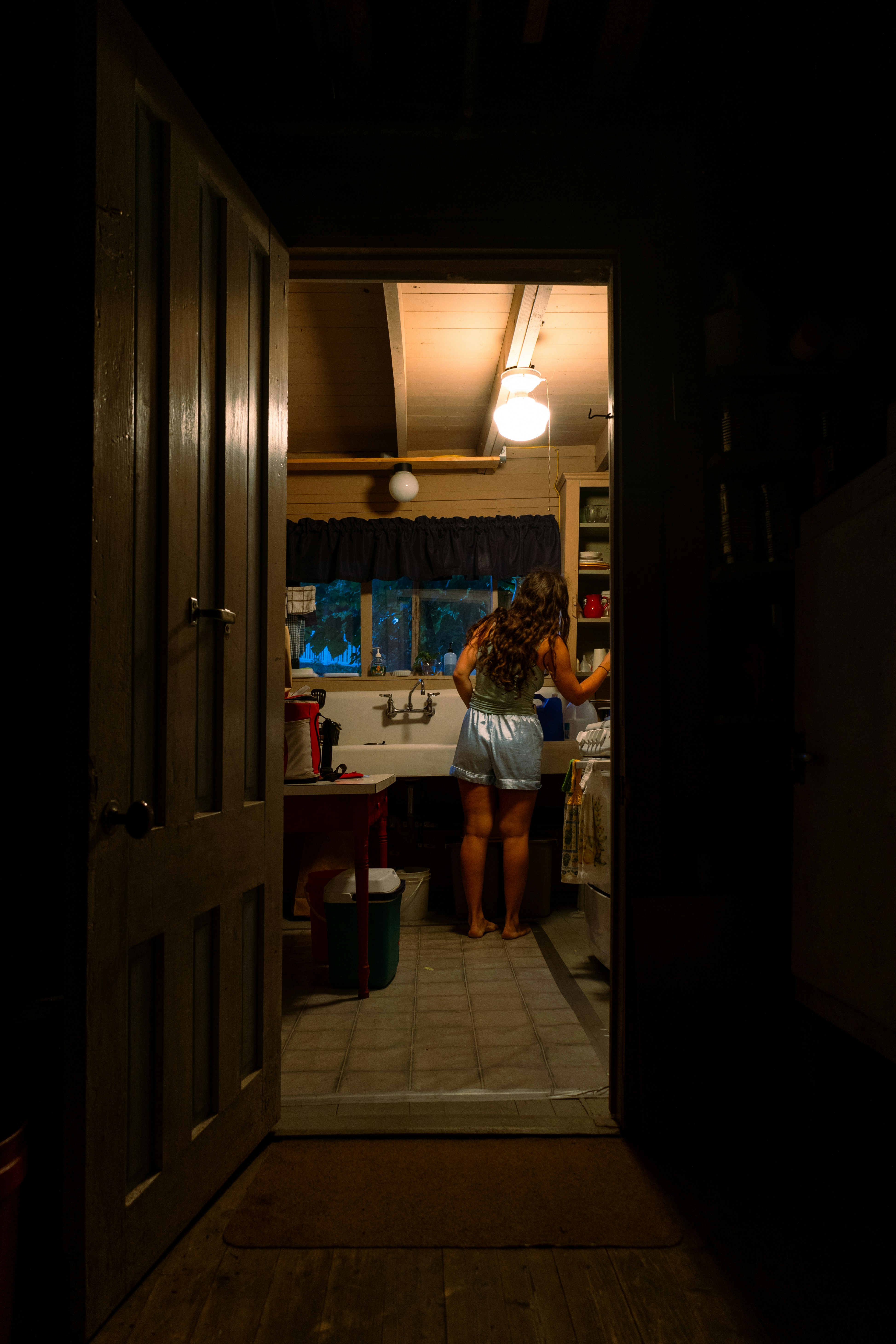 A woman standing in the doorway of a dark room
