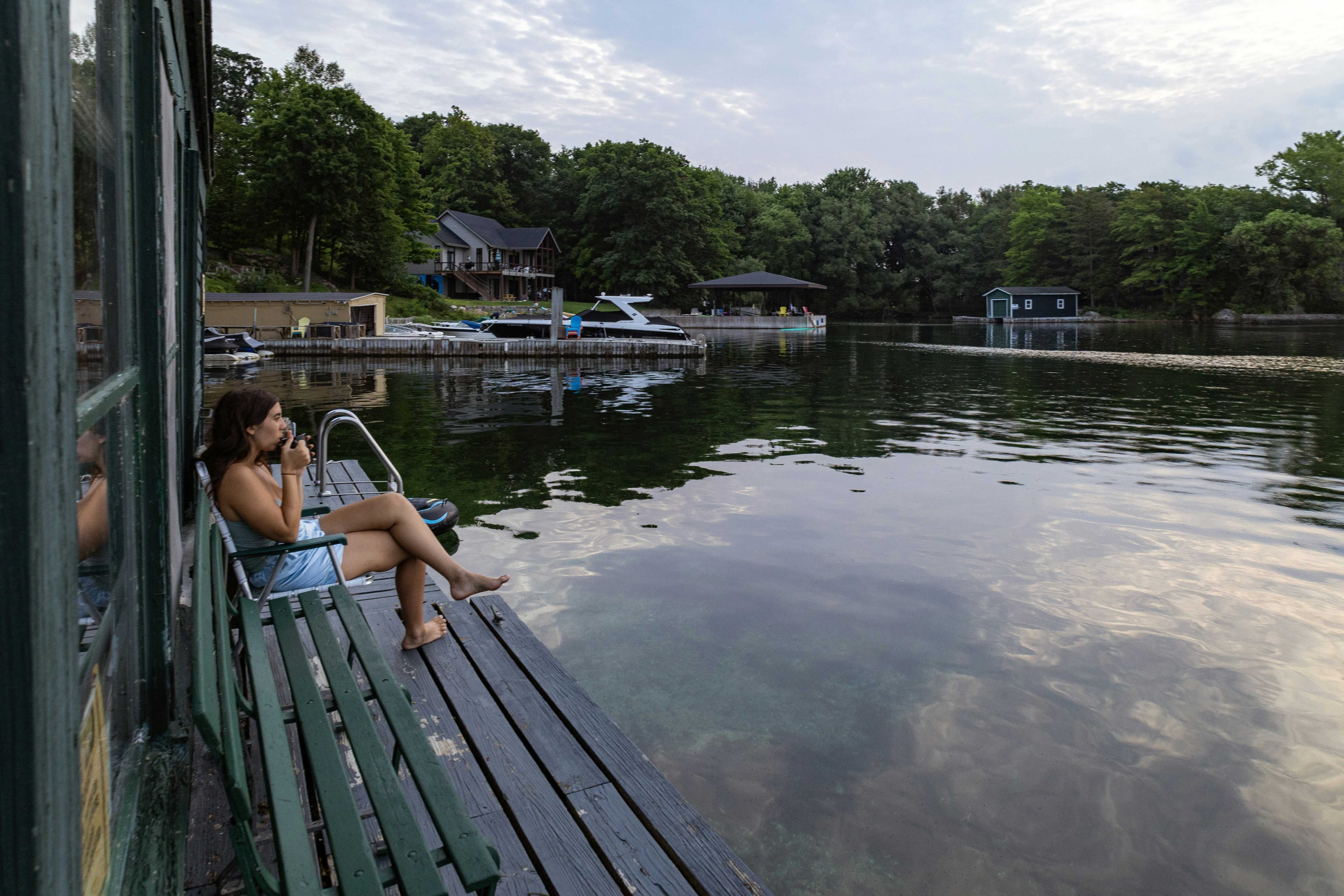 A woman sitting on a bench next to a body of water