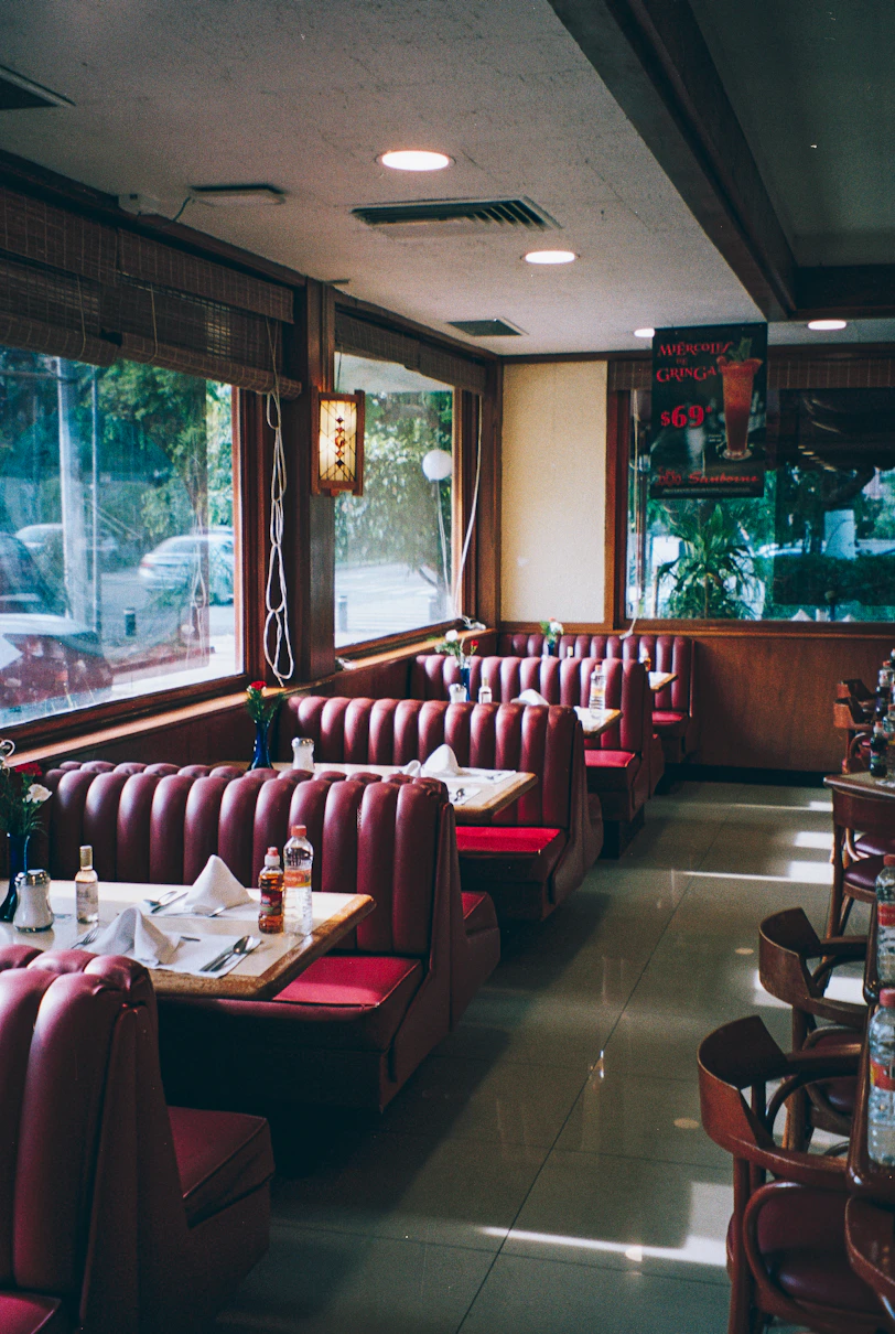 A restaurant with red booths and tables and windows