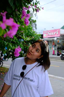 A woman standing on a sidewalk next to a tree
