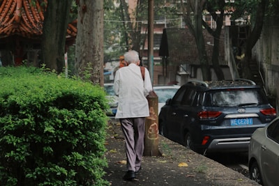 A man walking down a street next to parked cars
