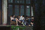 A group of people sitting on a porch next to a tree