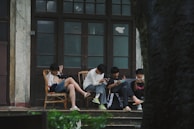 A group of people sitting on a porch next to a tree