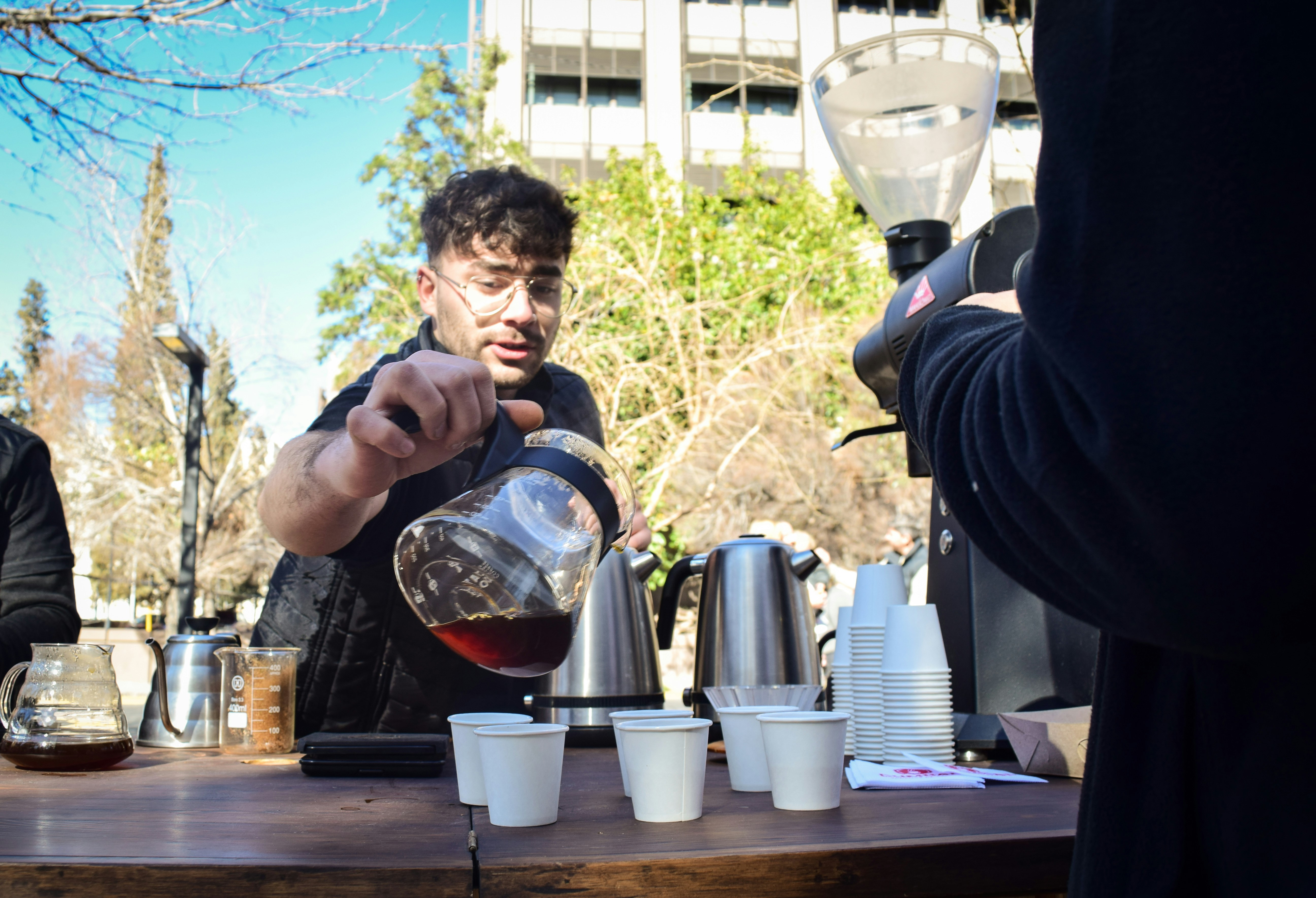 Man pouring filter coffee into cups at an outdoor table