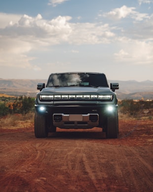 A pick up truck driving down a dirt road