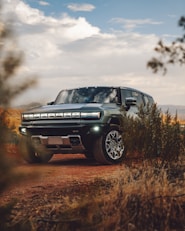 A green truck driving down a dirt road