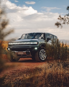 A green truck driving down a dirt road